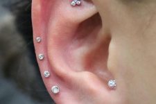 a bold ear with a faux rook, four helix, triple lobe piercings done with white gold studs of various kinds