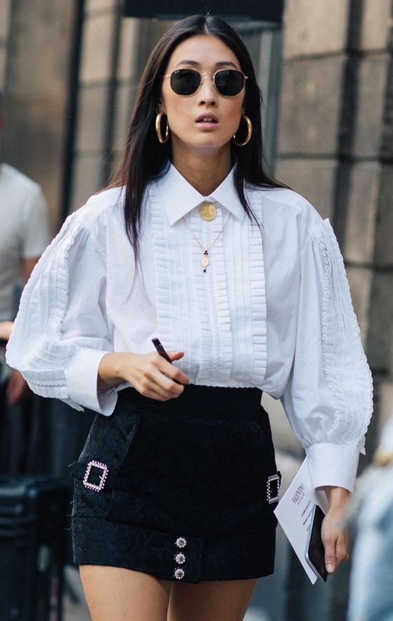 a bold look with an oversized white shirt with detailing, a black denim mini with embellishments, layered necklaces and statement earrings