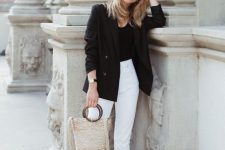 a business outfit with a black top, blazer, white jeans, brown slides and a woven bag that hints on vacation