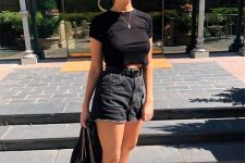 a casual summer outfit with a black cropped t-shirt, black high waisted denim shorts, white trainers and a black jacket
