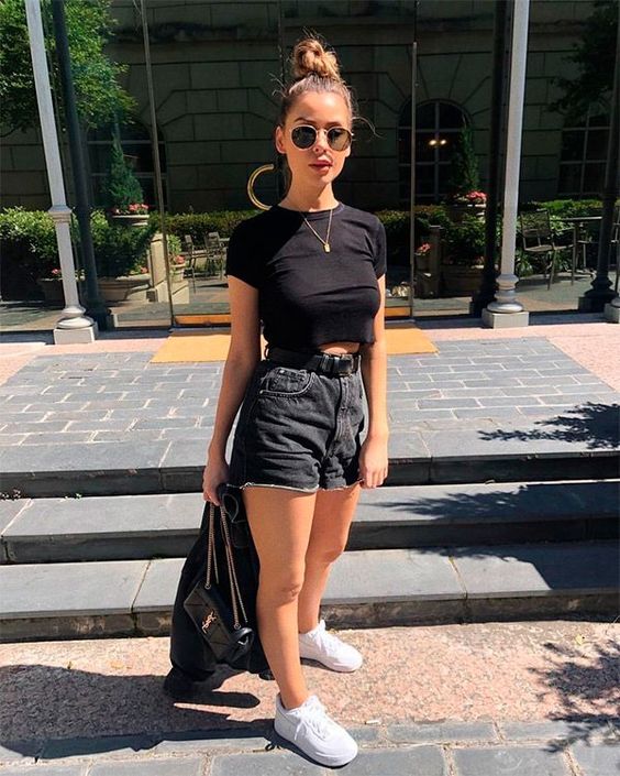 a casual summer outfit with a black cropped t-shirt, black high waisted denim shorts, white trainers and a black jacket