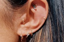 a chic ear stack with a triple lobe, tragus, helix and faux rook piercing done with gold hoops and studs