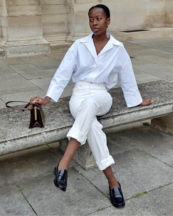 a classy look with an oversized white shirt, white cuffed jeans, black lacquer shoes and a small black bag