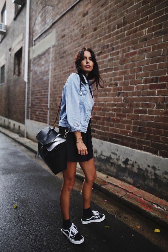 a cold summer day outfit with a bleached denim jacket, a black denim mini, black sneakers and socks, a black bag