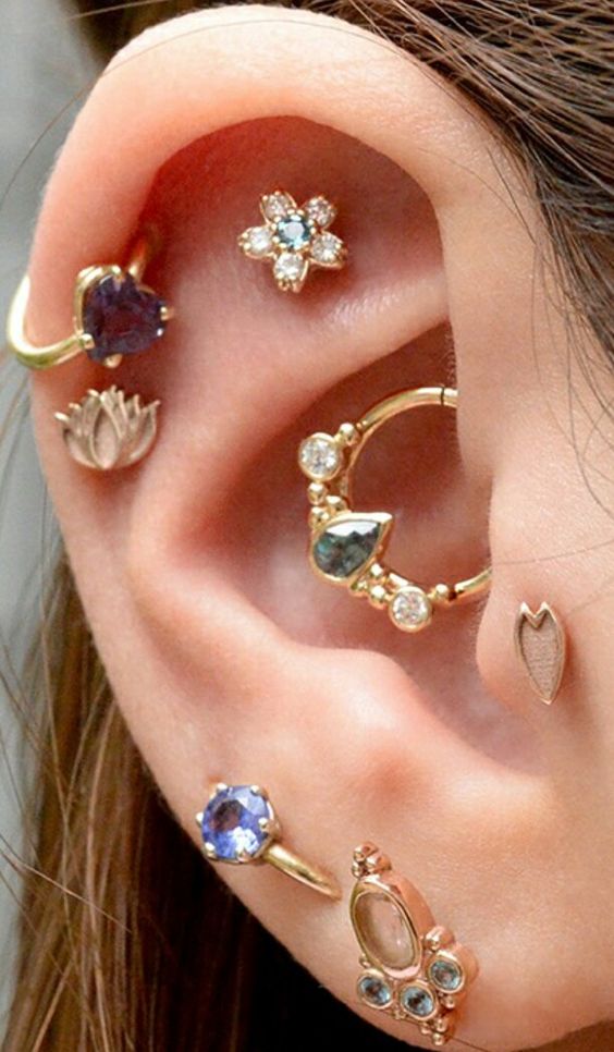 a colorful ear stack with a faux rook, double helix, daith, tragus and double lobe piercing done with colorful studs and hoops