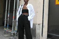 a contrasting summer outfit with a bra top, high waisted wideleg trousers, black slides, an oversized white shirt, a black bag