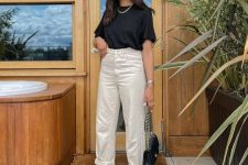 a contrasting work look with white cuffed jeans, a black t-shirt, a chain necklace, black strappy shoes and a black bag