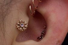 a glam look with a triple forward helix piercing, tragus, triple conch and stacked lobe piercing done with hoops and studs