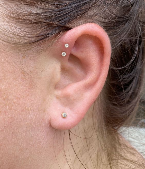 a laconic ear look with a double forward helix piercing and a lboe one all done with matching gold studs is always a good idea