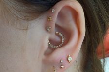 a lovely ear look with a triple forward helix piercing, a daith and a multiple lobe one, with studs and hoops of gold