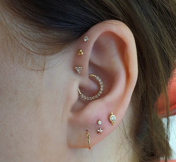 a lovely ear look with a triple forward helix piercing, a daith and a multiple lobe one, with studs and hoops of gold