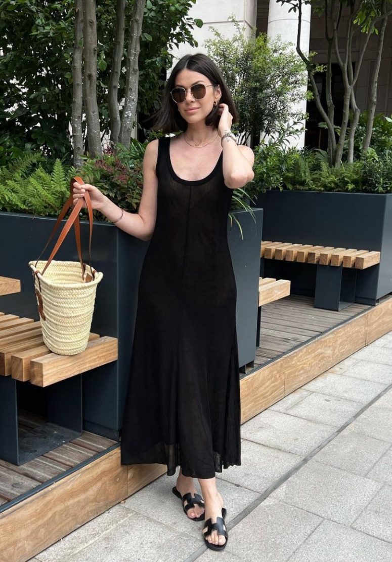 a lovely semi-sheer black tank midi dress with a scoop neckline, black slides and a woven bag are a lovely look for summer