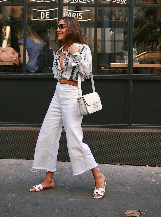 a printed blouse, white wide jeans, white slides and a small white bag are a lovely summer look