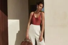a refined and minimalist summer look with a burgundy bodysuit, white wideleg pants, black sandals and a wooden bag