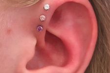 a simple triple forward helix piercing done with matching studs that create an ombre effect looks cool