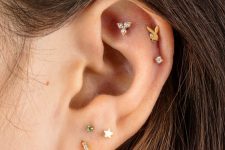 a stacked ear with a faux rook, double helix and triple lobe piercing done with gold studs and a hoop