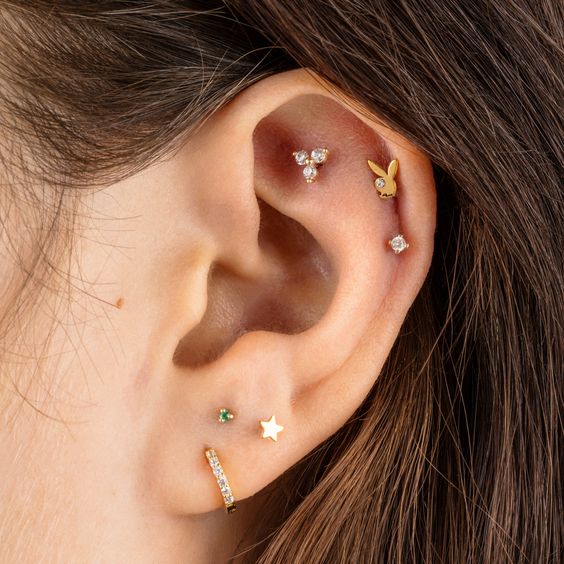 a stacked ear with a faux rook, double helix and triple lobe piercing done with gold studs and a hoop