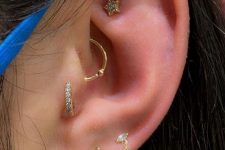 a stylish ear look with a faux rook, daith, tragus and triple lobe piercing done with gold studs and hoop earrings