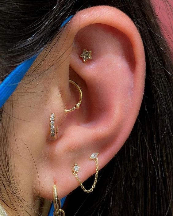 a stylish ear look with a faux rook, daith, tragus and triple lobe piercing done with gold studs and hoop earrings