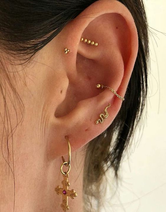 a subtle ear stack with mutiple lobe, conch, forward helix and faux rook piercing done with gold hoops, studs and even chains