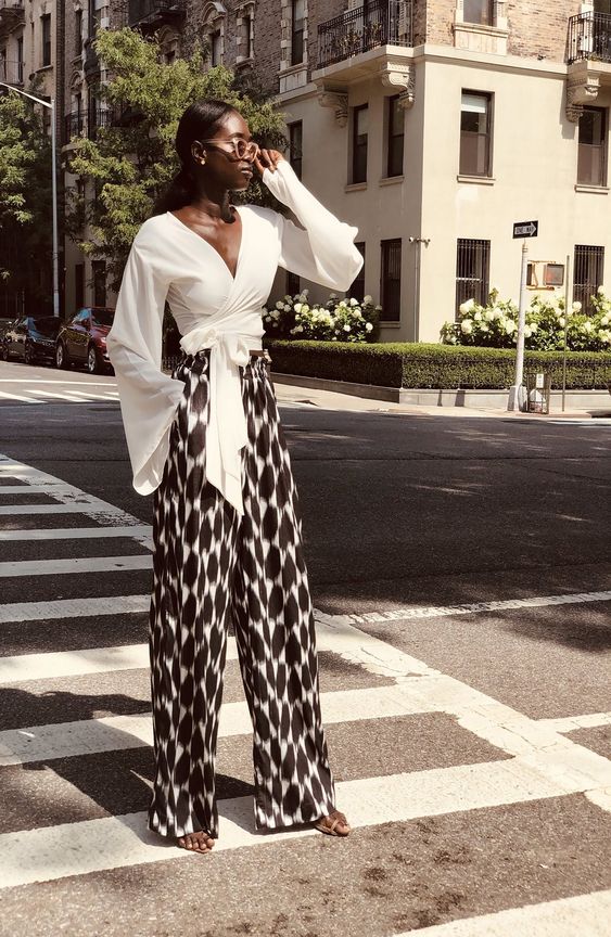 a summer party look with a white cropped and tied up top with bell sleeves, black and white printed palazzo pants