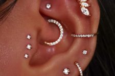 a super bold and chic ear set with stacked lobe, conch, helix, faux rook, triple tragus and forward helix piercings done with matching studs and hoops