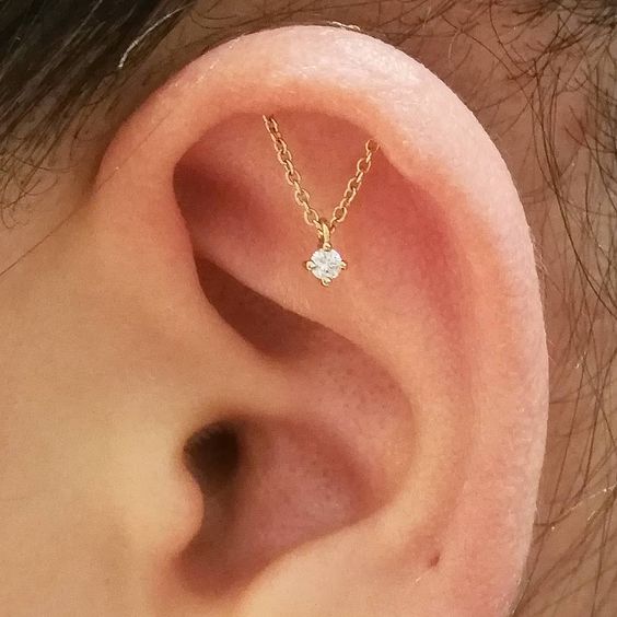 a super delicate hidden helix piercing with a gold chain with a rhinestone piece is a unique idea to go for