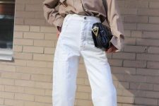 a taupe oversized shirt, white high waisted jeans, neutral sandals and a black bag for a stylish work look