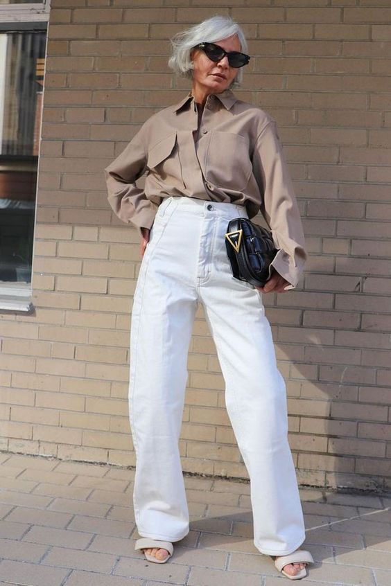 a taupe oversized shirt, white high waisted jeans, neutral sandals and a black bag for a stylish work look