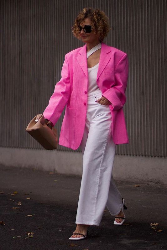 an edgy work look with white wideleg jeans, a white cutout top, a hot pink oversized linen black, heeled sandals and a beige bag
