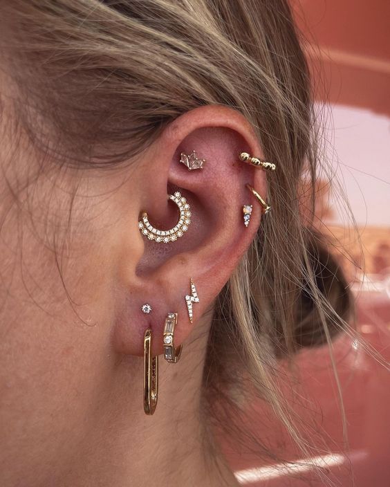 an extra bold ear stack with a stacked lobe, helix and a faux rook plus daith piercing all done with gold hoops and studs of various kinds