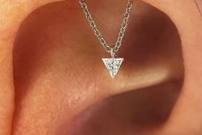 an invisible helix piercing with a chain and a triangle rhinestone, which is a unique jewelry piece that will add interest to your look