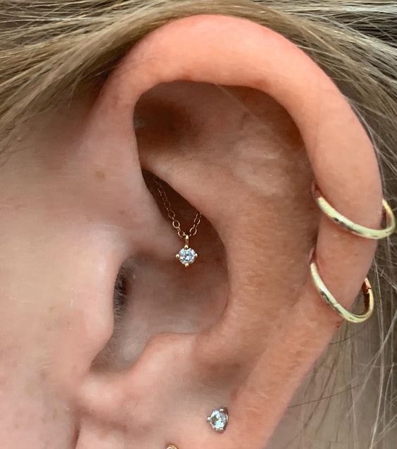 lobe, a double helix and hidden rook piercing done with studs, hoops and chain with a rhinestone are amazing