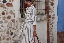 04 a midi linen striped shirtdress with side slits, cuffed sleeves, a sash, a woven bag with leather handles and leather slides