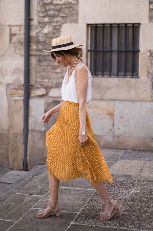 a romantic look with a white cami top, a yellow printed pleated midi, neutral lace up shoes, a pearl necklace and a straw hat