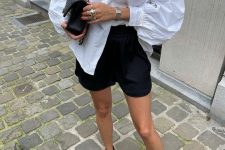 16 a white oversized shirt, black shorts, black strap up sandals, a black bag and statement accessories