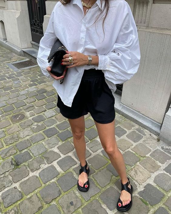 a white oversized shirt, black shorts, black strap up sandals, a black bag and statement accessories