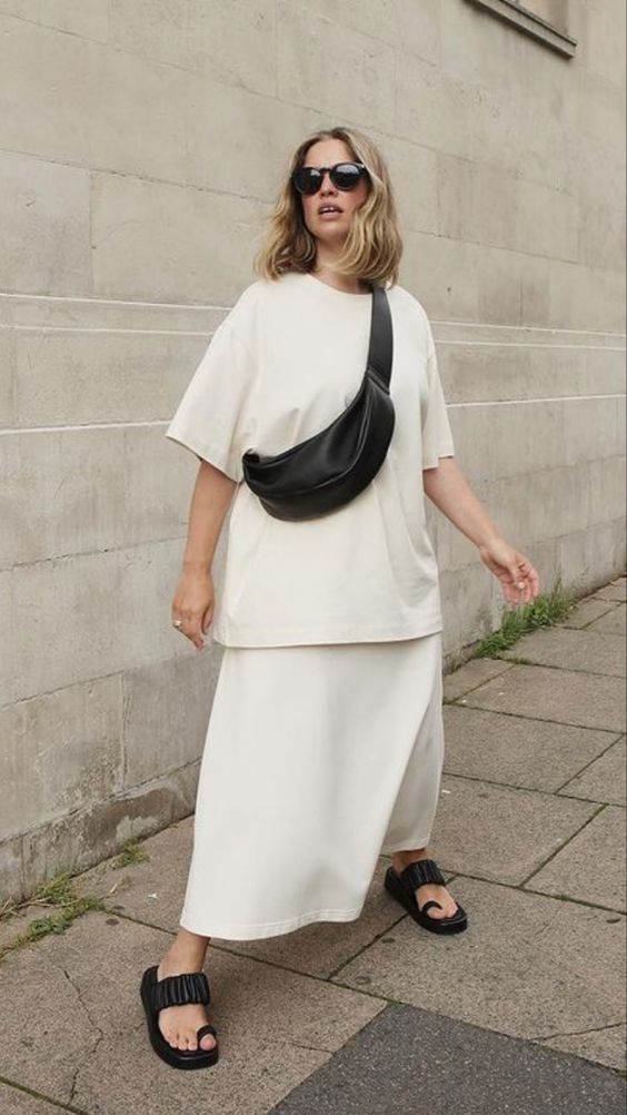 an all-minimalist outfit with a creamy t-shirt, a matching maxi skirt, black sandals and a black waistbag