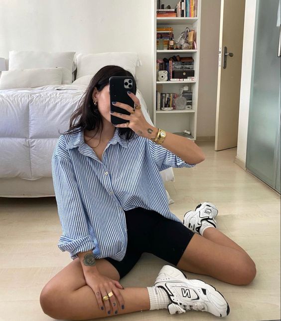 a blue thin stripe oversized shirt, black biker shorts, black and white trainers and white socks for every day