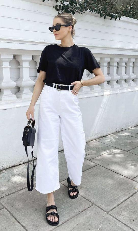 a contrasting minimalist outfit with a black t-shirt, white cropped jeans, black sandals and a black bag