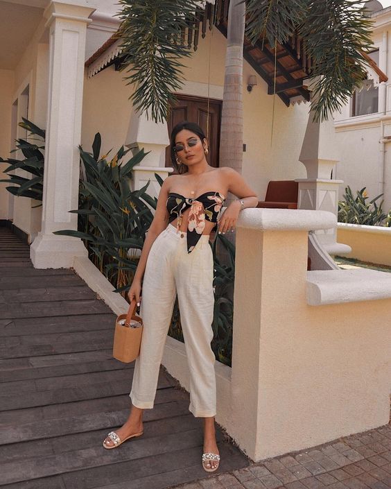 a floral knotted crop top, white linen pants, pearl slides and a small bucket bag plus sunglasses