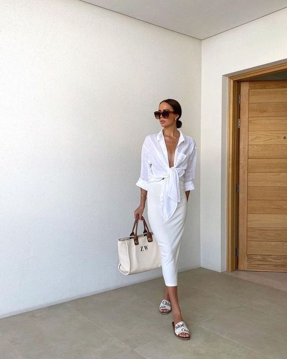 a super neutral look with an oversized knotted shirt, a pencil midi skirt, slides and a large tote for a vacation