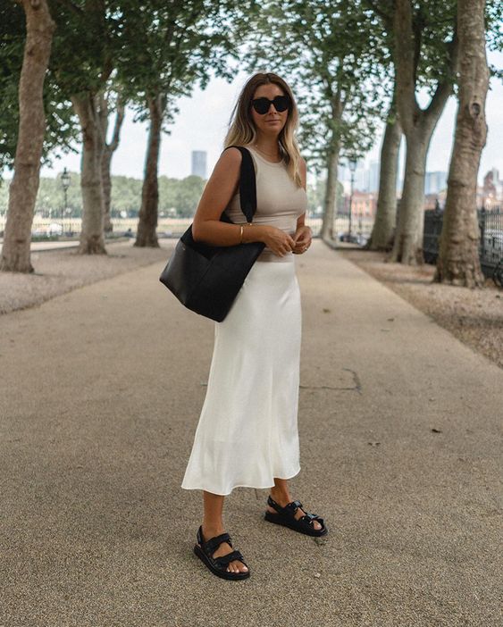 a minimalist summer look with a tan tank top, a white slip midi skirt, black sandals and a black tote