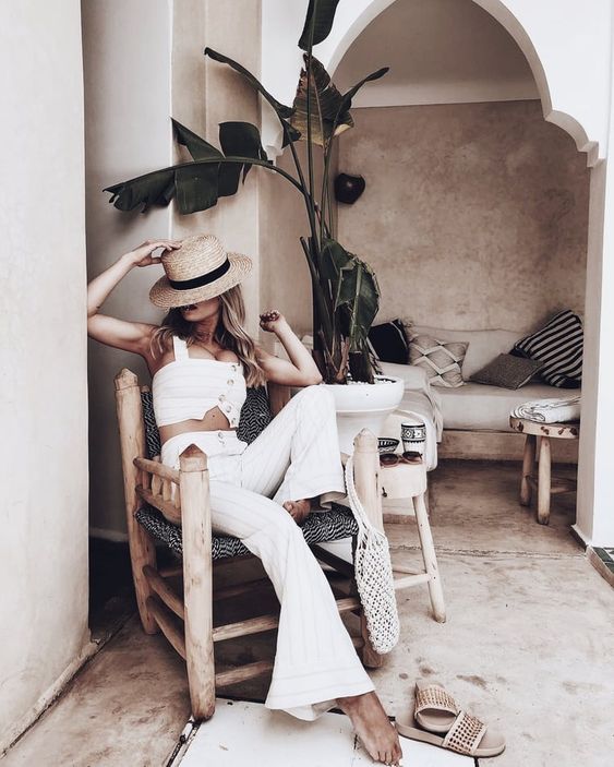 a vacation outfit with a thin strip set with a crop top and flare pants, neutral slides and a straw hat is sexy