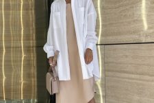 31 a tan asymmetrical midi dress, an oversizd white shirt, tan slippers and a matching bag for summer