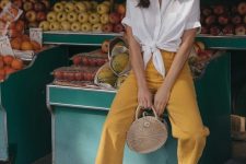 31 a white knotted short sleeve shirt, yellow cropped jeans, white slipper mules and a woven round bag for a summer vacation