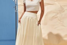 With golden earrings, beige ruffled crop top and white leather sandals