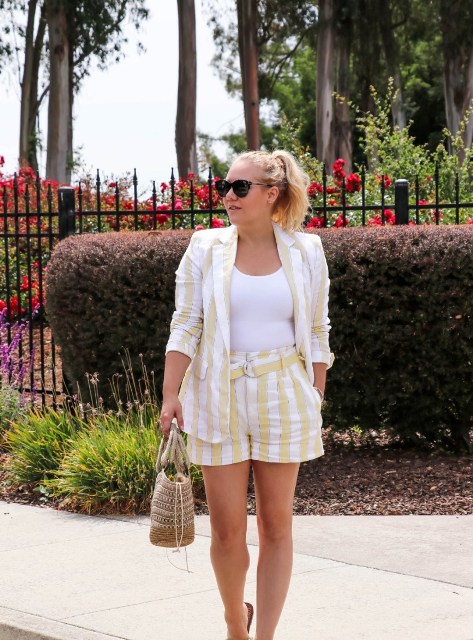 With sunglasses, white fitted top, white and light yellow striped linen blazer, beige bag and flat sandals