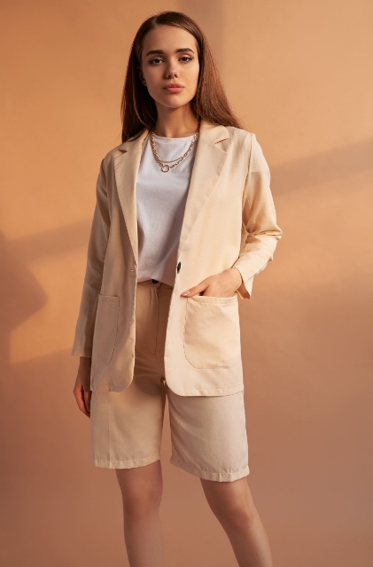 With white t-shirt, beige long blazer and golden necklace