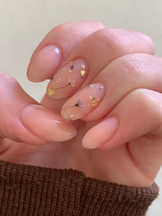 a beautiful nude manicure with two accent nails done with dried flowers and gold leaf is a gorgeous idea for spring or summer